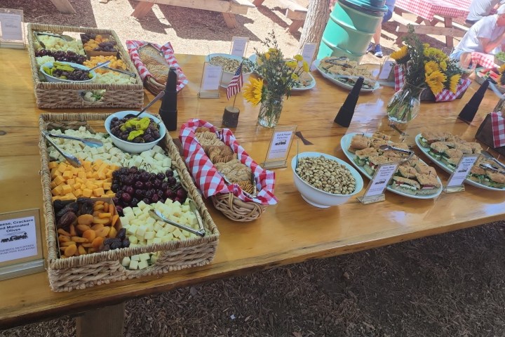 Buffet table with fruit, cookies, nuts, and flowers in baskets.