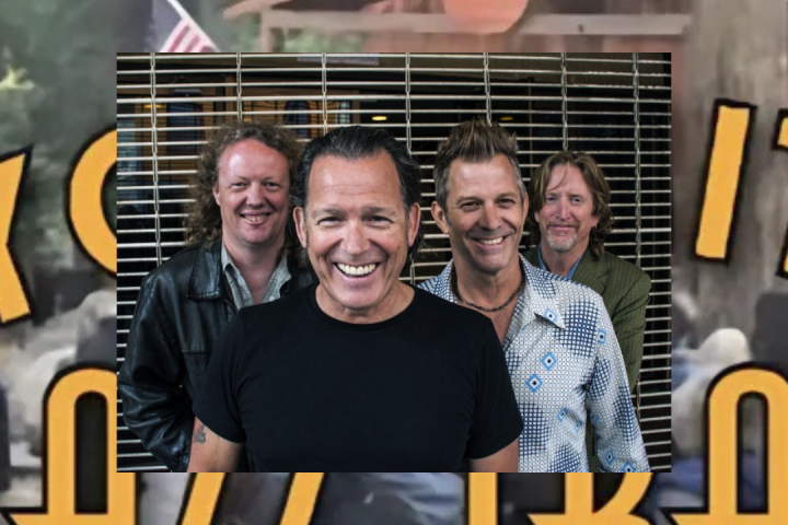 Tommy Castro et al. standing next to a guitar