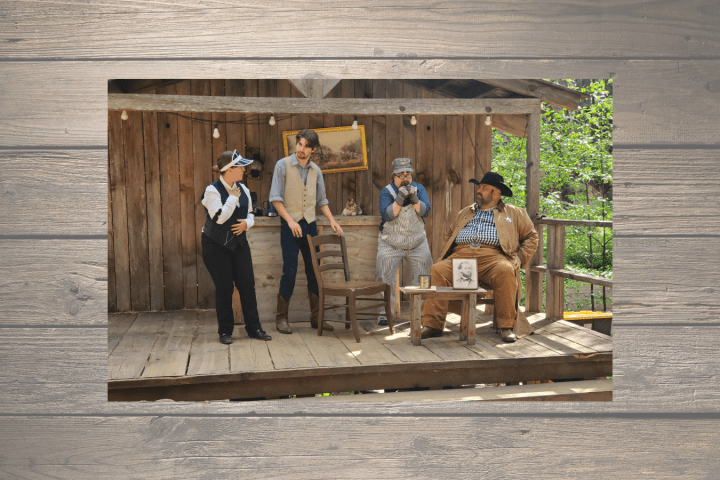 Four people in Old West attire performing on wooden porch stage.