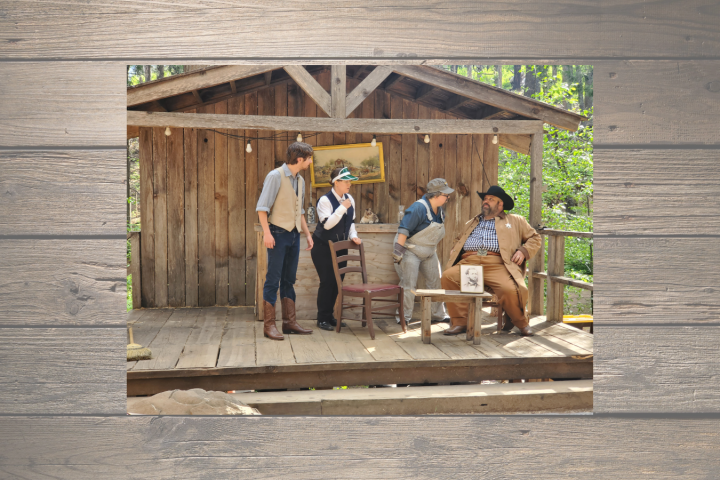 Four people in western attire on a rustic wooden porch.